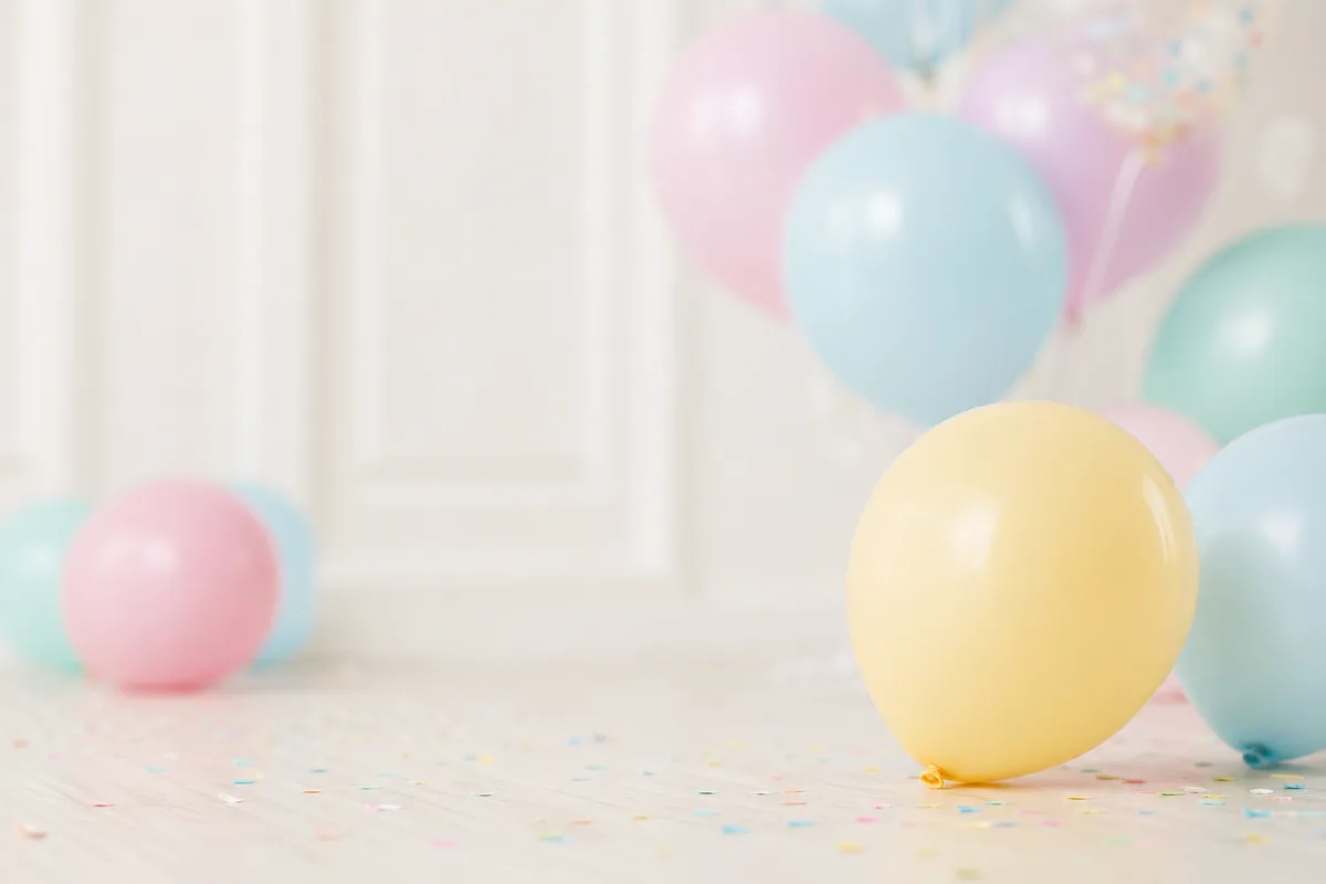 Fröhliche, zurückhaltende Pastelltöne mit partyartiger Stimmung im Hintergrund, ohne erkennbare Personen – symbolisch für Kindergeburtstag planen.